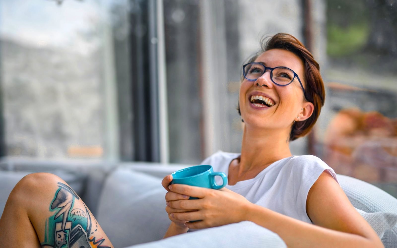 Persona relajada con una taza de café mirando el atardecer desde su balcón